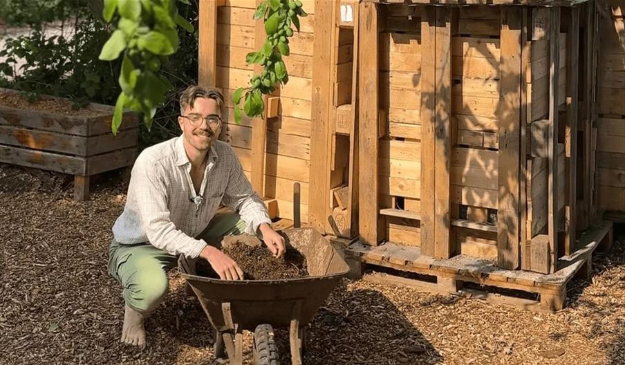 Generation Soil - man crouched down by a wheelbarrow full of soil