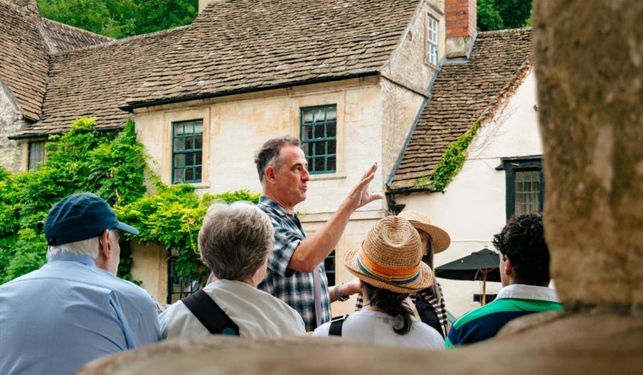 Tour guide sharing their knowledge with the group in a village in the Cotswolds