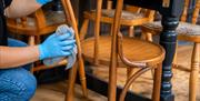 Someone cleaning wooden bar restaurant chairs with a cloth