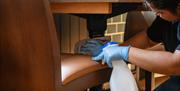 A lady cleaning underneath a wooden pub table