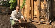 Generation Soil - man crouched down by a wheelbarrow full of soil