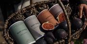 A woven basket containing figs and a selection of Natural Spa Factory branded toiletries.