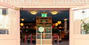 A set of open doors leading into Ritorno Lounge. The company name is visible above the doorway. A sign inside the doorway reads, 'please wait to be se