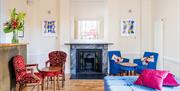 A room at the Clifton Hotel containing a mixture of red and blue armchairs and an ornate fireplace