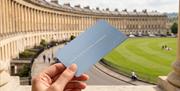 A close up of a hand holding a member card with the Royal Crescent in the background.